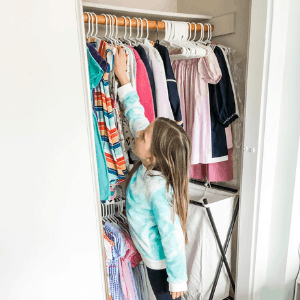 girl reaching for clothes in closet