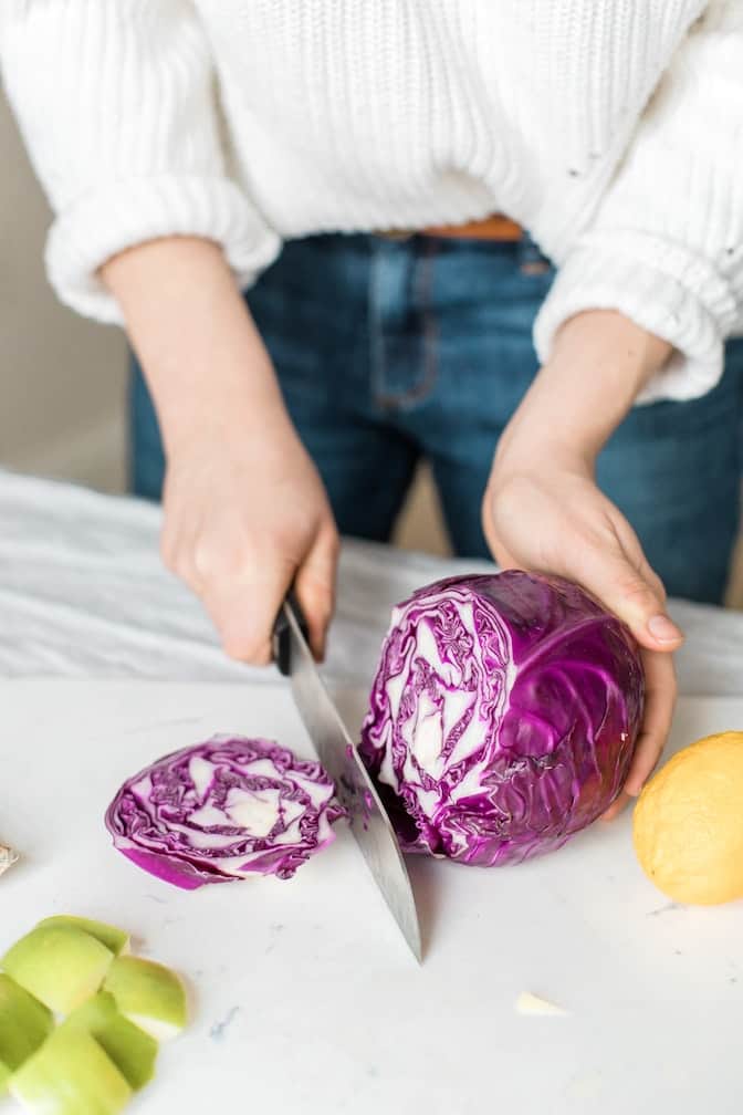 woman chopping purple cabbage