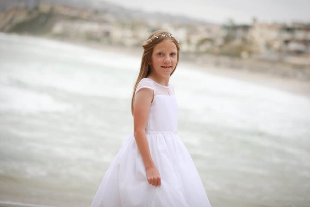 Girl in First Communion dress on the beach